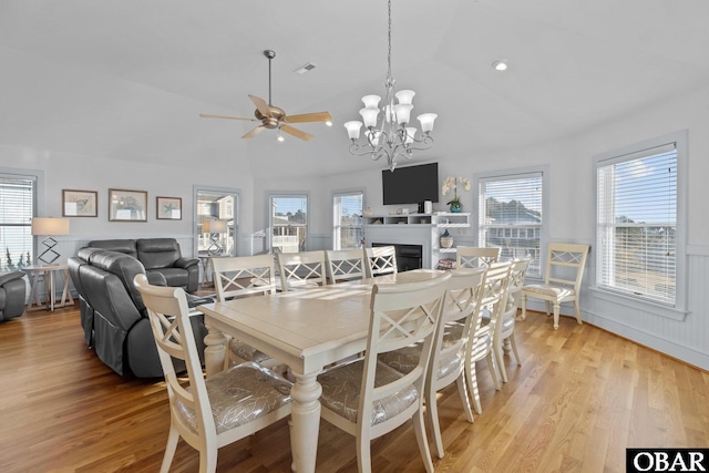 dining space with lofted ceiling, light wood finished floors, wainscoting, and visible vents