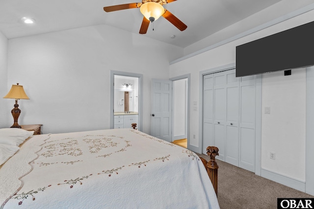 carpeted bedroom featuring a closet, vaulted ceiling, ensuite bathroom, and ceiling fan