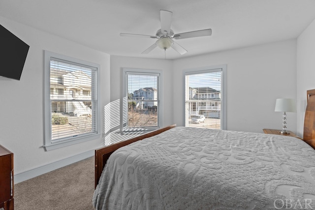 carpeted bedroom with ceiling fan and baseboards