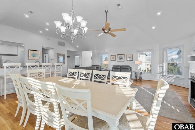 dining room with visible vents, high vaulted ceiling, a fireplace, and light wood-style flooring