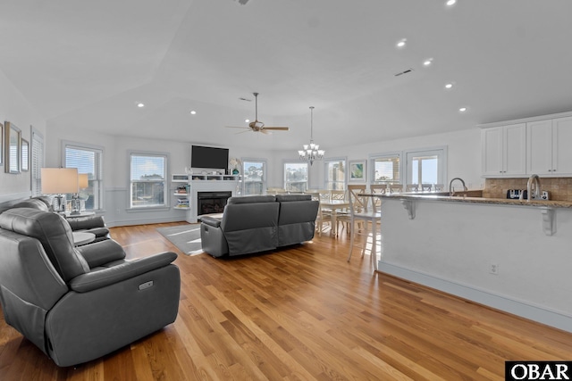 living room featuring light wood finished floors, visible vents, vaulted ceiling, a fireplace, and recessed lighting