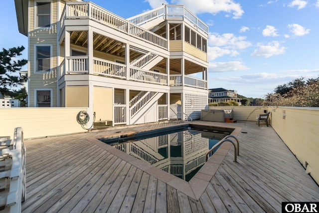 rear view of house with a hot tub, fence, and a wooden deck