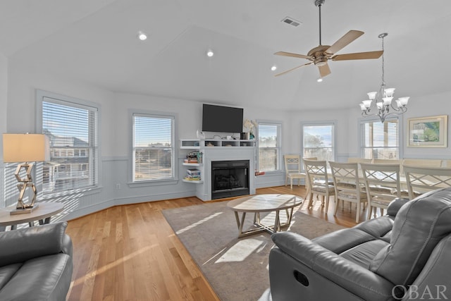 living room with a wainscoted wall, a fireplace with flush hearth, visible vents, and a wealth of natural light