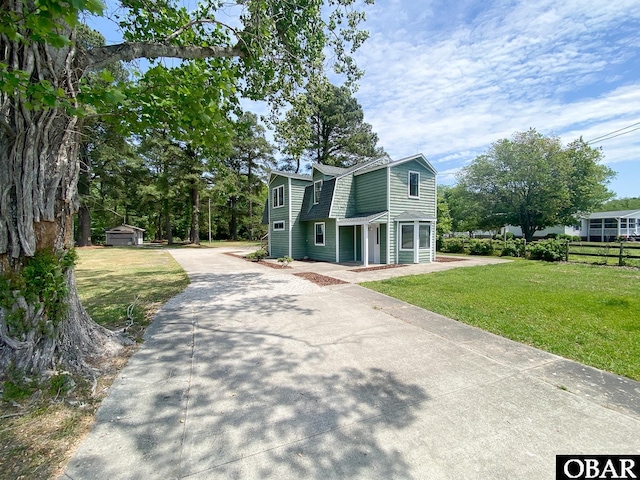 5707 Caratoke Hwy, Poplar Branch, NC 27965 - view of front of house featuring an outdoor structure, a front lawn, aphalt driveway, and fence