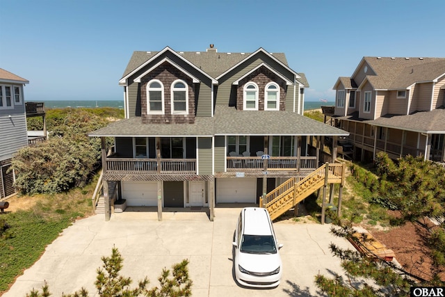 view of front facade with driveway, a garage, roof with shingles, covered porch, and stairs