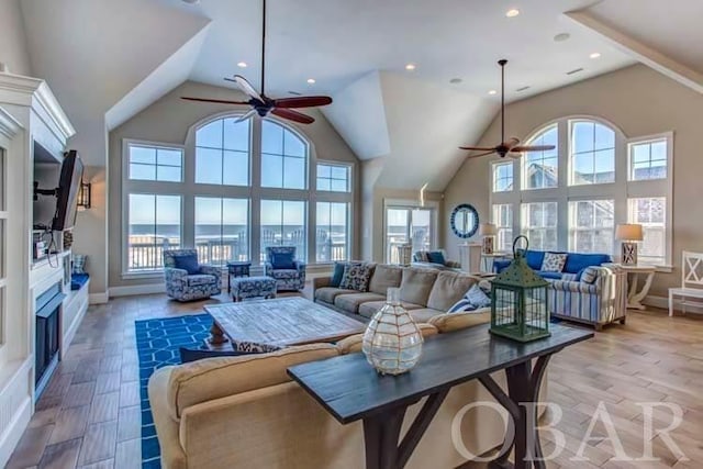 living area with recessed lighting, light wood-style floors, a ceiling fan, high vaulted ceiling, and baseboards