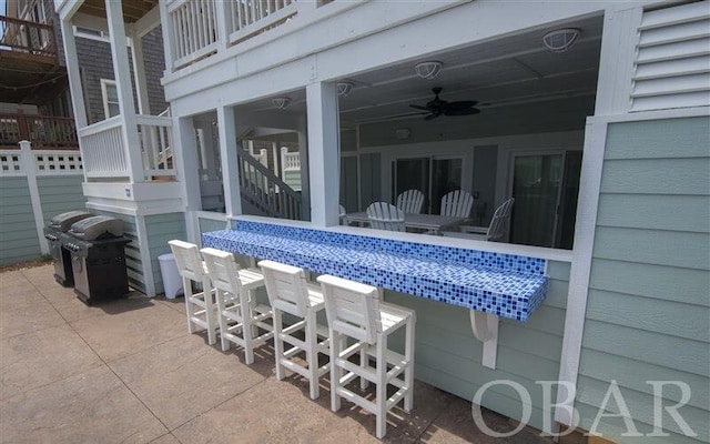 view of patio with ceiling fan, grilling area, and an outdoor bar