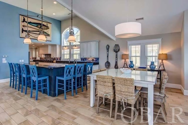 kitchen with a peninsula, a breakfast bar, visible vents, tasteful backsplash, and pendant lighting