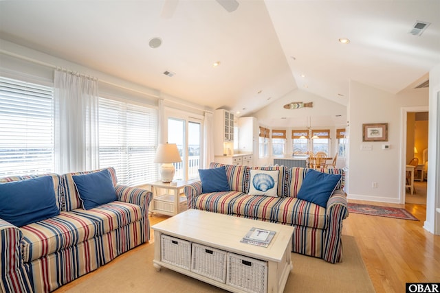 living area featuring lofted ceiling, baseboards, visible vents, and light wood-type flooring