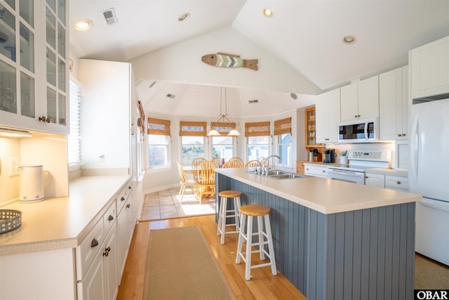 kitchen with a breakfast bar, a sink, white appliances, white cabinets, and light countertops