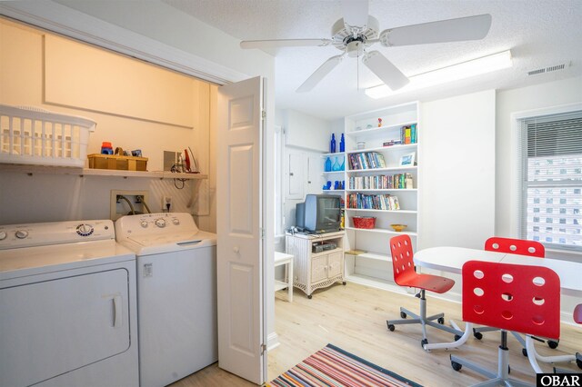 washroom with visible vents, laundry area, separate washer and dryer, light wood-style floors, and a textured ceiling