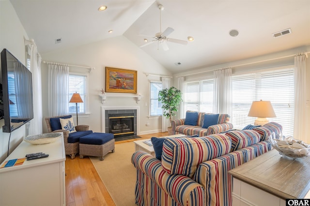 living area featuring visible vents, lofted ceiling, light wood-style flooring, and a tile fireplace