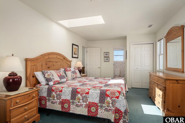 bedroom featuring a skylight, visible vents, dark colored carpet, and a closet