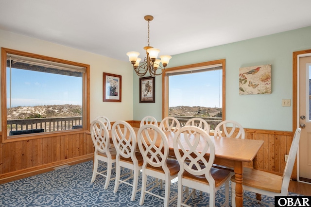 dining space featuring a wealth of natural light, wooden walls, and wainscoting