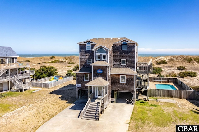 view of front facade with a balcony, stairway, a fenced in pool, and fence