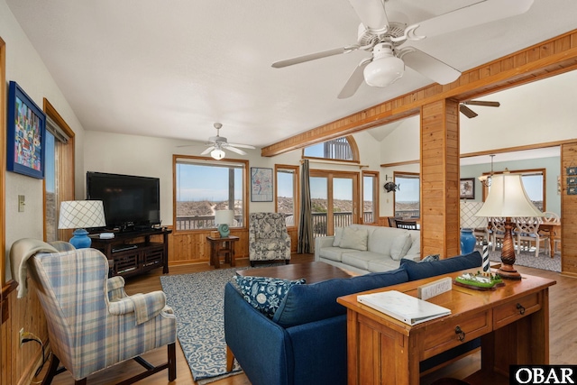 living area with wood finished floors, lofted ceiling with beams, a ceiling fan, and wainscoting