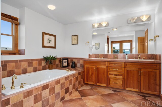 bathroom featuring tile patterned floors, a sink, a jetted tub, and double vanity