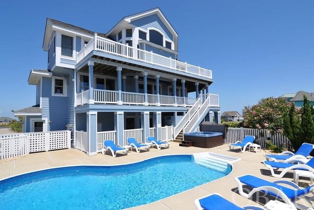 rear view of property featuring a hot tub, fence, a fenced in pool, and a patio