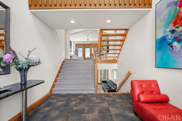 stairs with arched walkways, recessed lighting, a ceiling fan, baseboards, and stone finish flooring