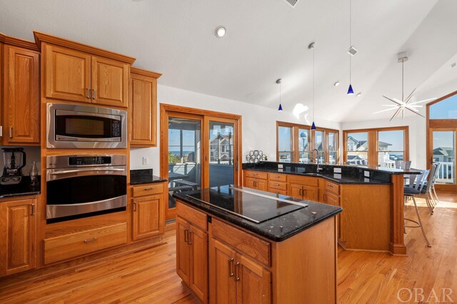 kitchen with stainless steel appliances, a sink, a center island, a kitchen bar, and pendant lighting