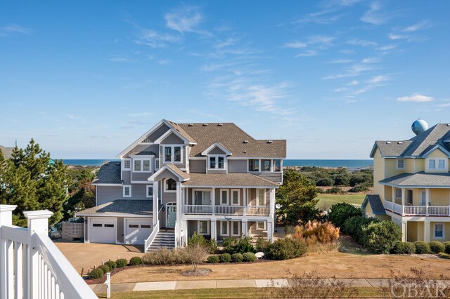 view of front facade featuring a garage, driveway, a water view, and a balcony