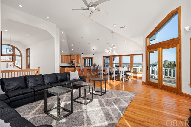 living area featuring high vaulted ceiling, light wood-type flooring, visible vents, and recessed lighting