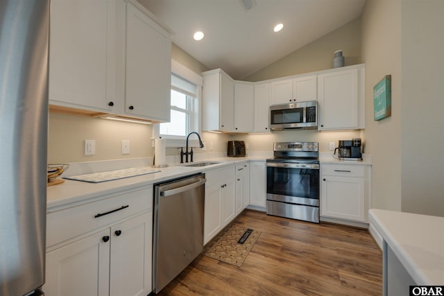 27197 Black Dog Ln Lot 9, Salvo, NC 27972 - kitchen with appliances with stainless steel finishes, vaulted ceiling, white cabinetry, wood finished floors, and light countertops