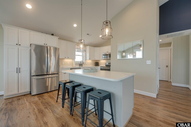 27197 Black Dog Ln Lot 9, Salvo, NC 27972 - kitchen with stainless steel appliances, white cabinets, light wood-style flooring, light countertops, and high vaulted ceiling