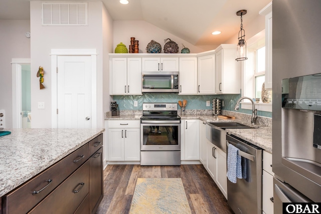 kitchen with visible vents, lofted ceiling, white cabinets, stainless steel appliances, and a sink