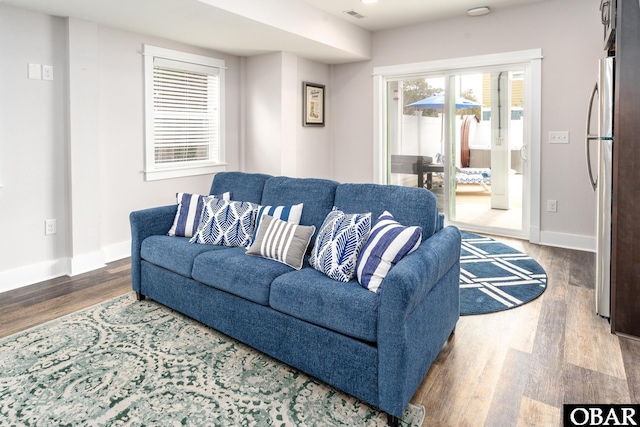 living area with visible vents, wood finished floors, and baseboards