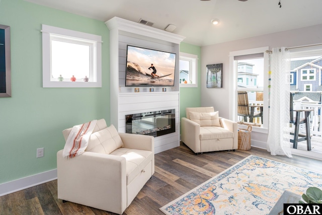 sitting room with baseboards, a large fireplace, visible vents, and wood finished floors