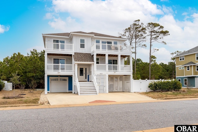 coastal inspired home featuring a gate, fence, driveway, an attached garage, and a shingled roof