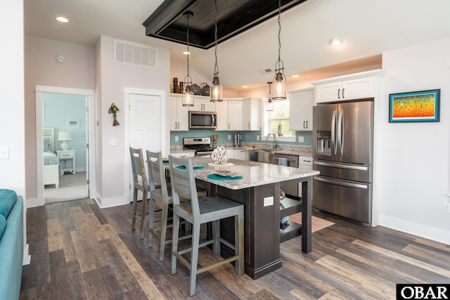 kitchen with visible vents, white cabinetry, appliances with stainless steel finishes, and a breakfast bar area