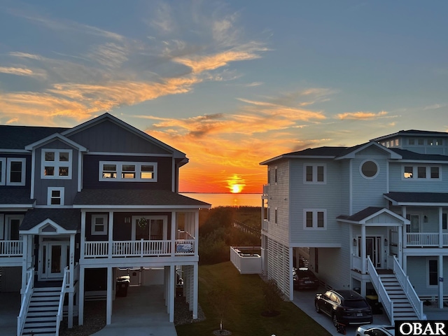 raised beach house with a carport, stairway, and a shingled roof