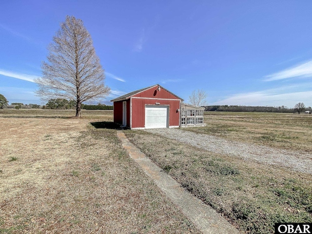 view of outdoor structure featuring an outbuilding, driveway, and a rural view