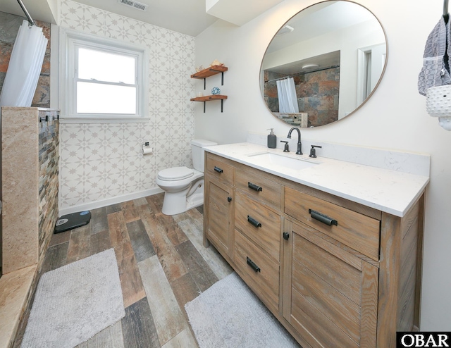 bathroom with visible vents, toilet, vanity, wood finished floors, and baseboards