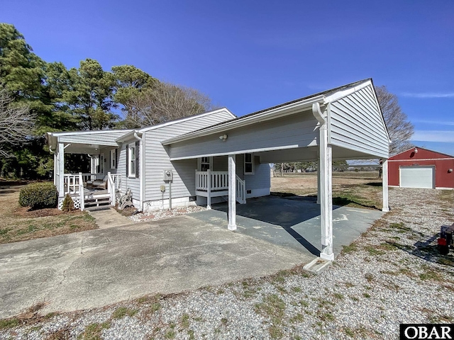 view of front of house with driveway, a porch, an attached carport, and an outdoor structure