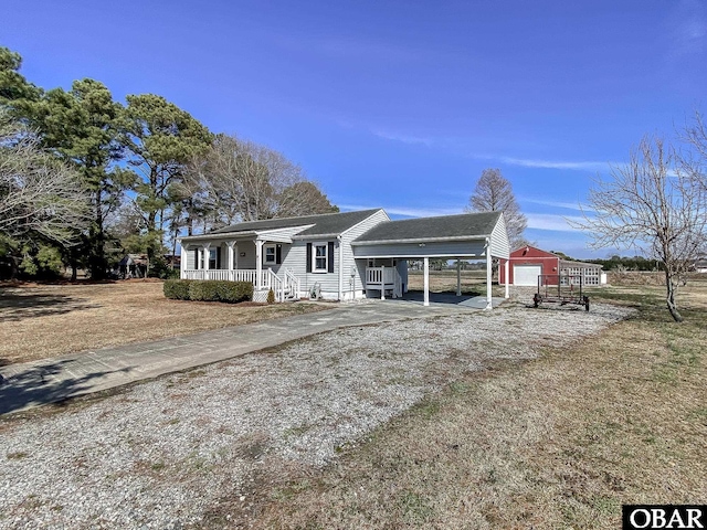 view of front of home featuring a carport, an outdoor structure, and driveway