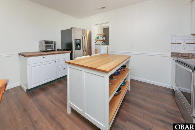 kitchen featuring visible vents, appliances with stainless steel finishes, washing machine and clothes dryer, white cabinetry, and wooden counters