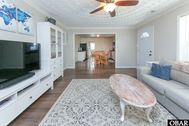 living area with baseboards, ornamental molding, and dark wood finished floors