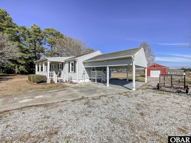 view of front of home featuring gravel driveway, covered porch, and an outbuilding