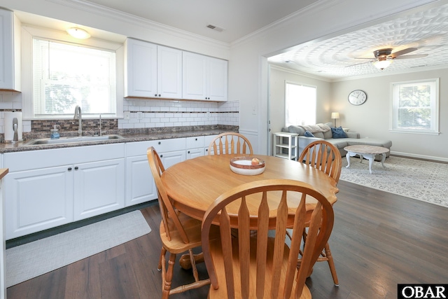 dining space with dark wood-style floors, ornamental molding, visible vents, and a ceiling fan