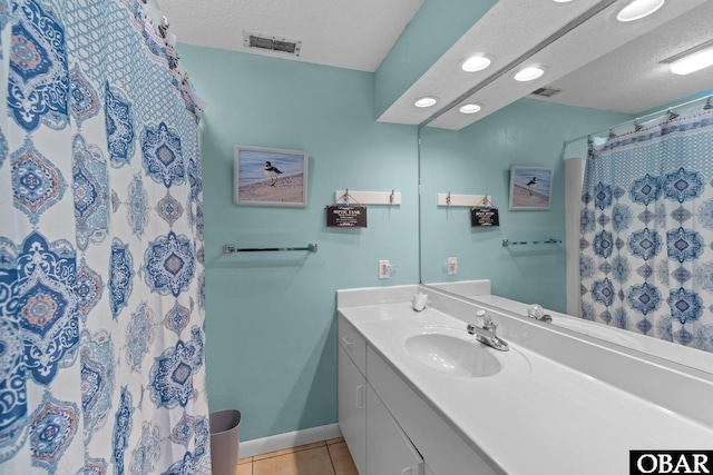 full bathroom featuring vanity, a textured ceiling, tile patterned floors, baseboards, and visible vents