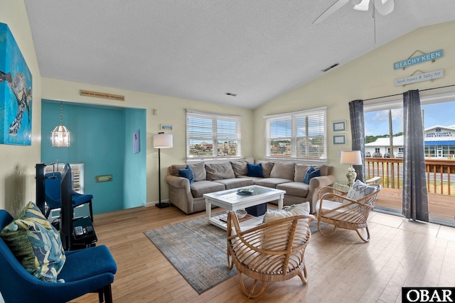 living area featuring vaulted ceiling, a wealth of natural light, wood finished floors, and visible vents