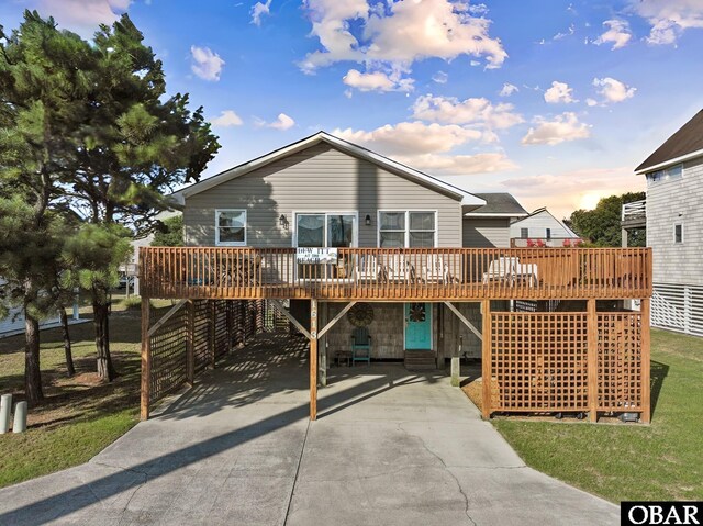 back of house with driveway, a wooden deck, and a carport
