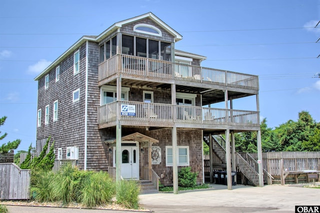 raised beach house featuring stairway and a sunroom