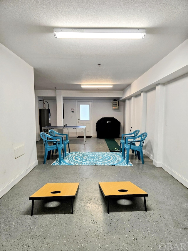 interior space featuring a textured ceiling, an AC wall unit, speckled floor, and baseboards