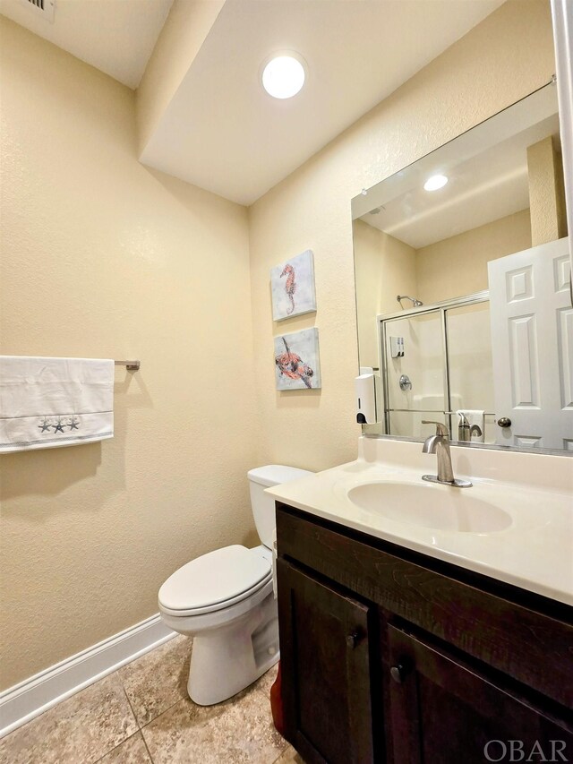 bathroom with baseboards, toilet, vanity, a shower stall, and recessed lighting