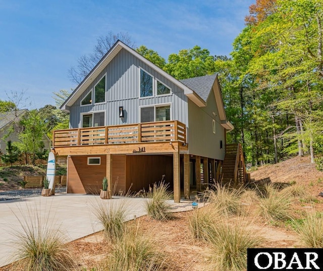 back of house featuring stairs, a deck, and driveway