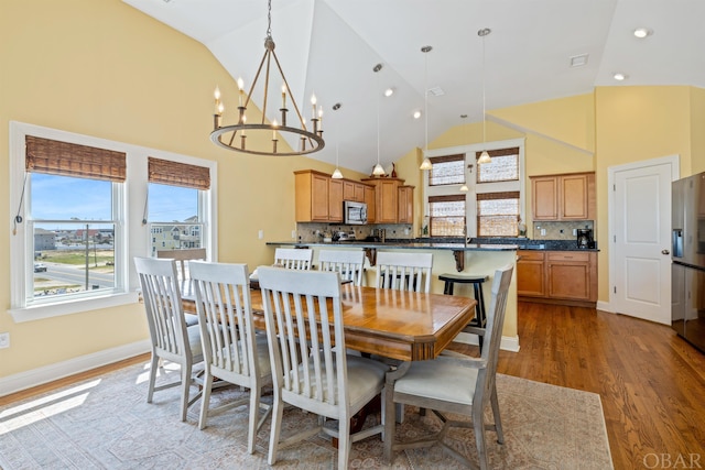 dining room featuring high vaulted ceiling, recessed lighting, wood finished floors, baseboards, and an inviting chandelier